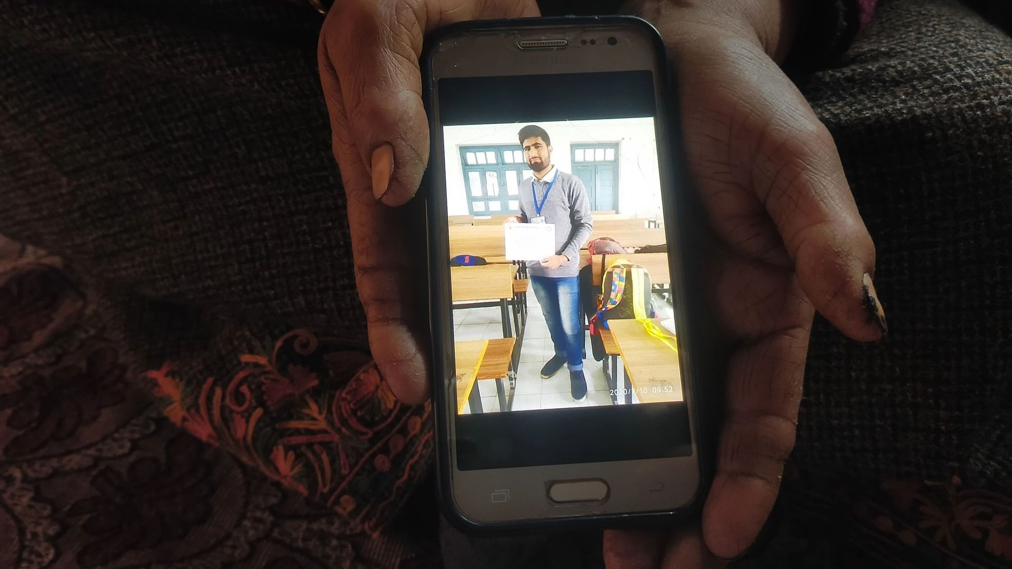<div class="paragraphs"><p>Hafeeza, Showkat's mother, holding a mobile phone displaying his pic.</p></div>