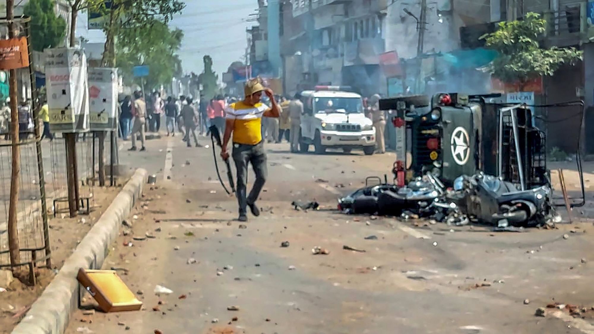 <div class="paragraphs"><p>A policeman near a burnt vehicle as police try to control the situation after a communal clash during the Ram Navami procession, in Himmatnagar, on Sunday, 10 April.</p></div>