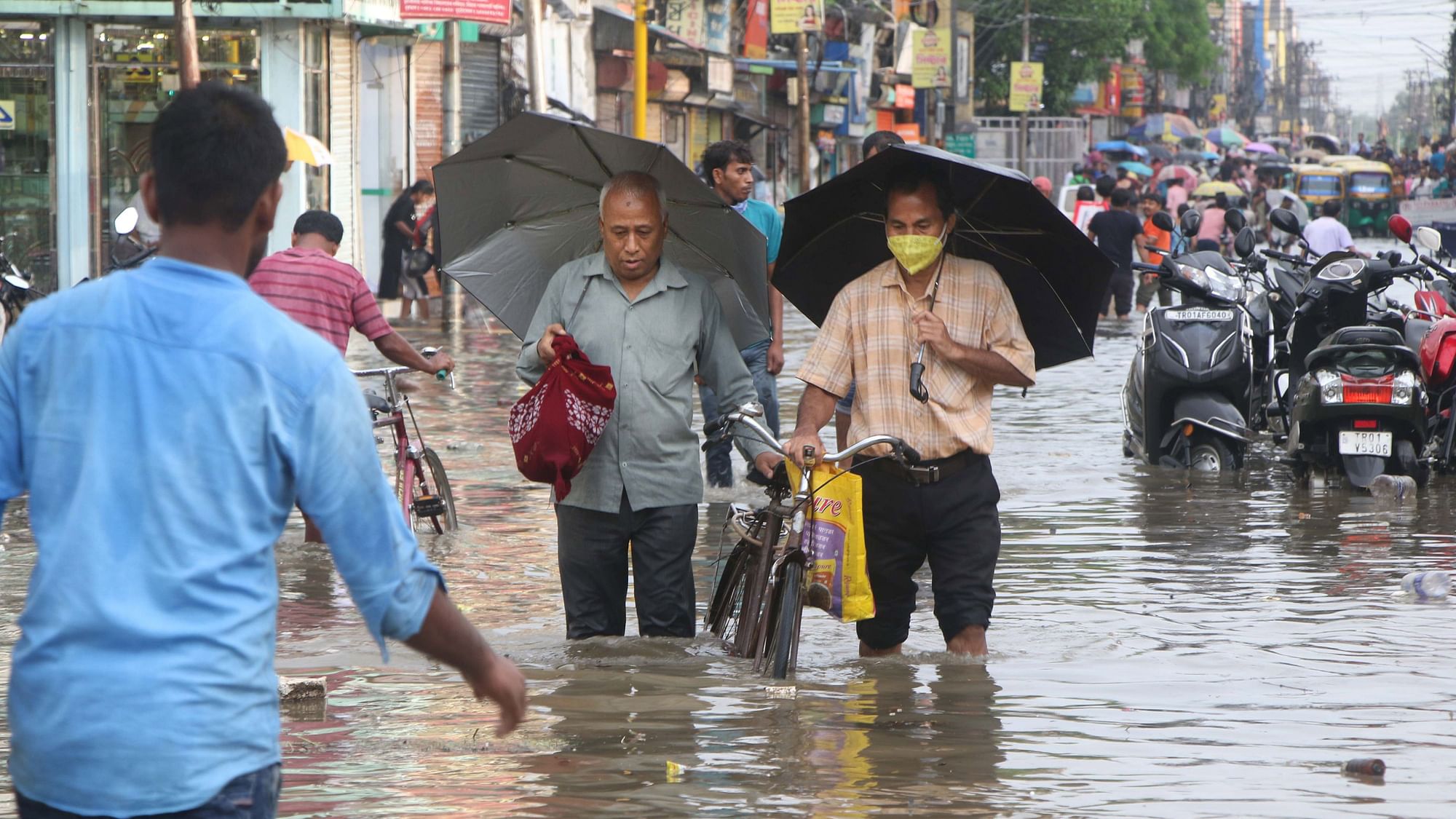 <div class="paragraphs"><p>Commuters wade through a waterlogged street following heavy rains, in Agartala on 19 May.</p></div>
