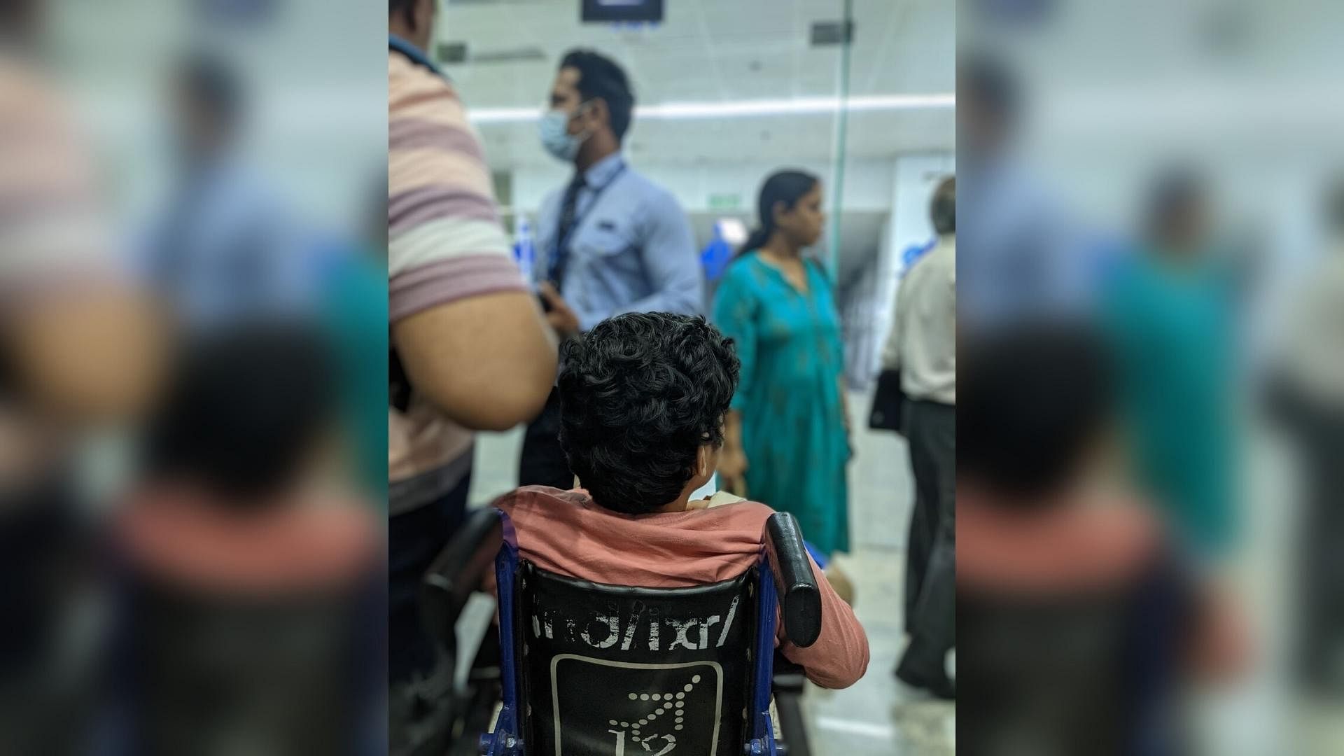Screenshot of backview of child sitting on Indigo6E wheelchair. Ranchi Airport Indigo staff can be seen on the background surrounded by copassengers trying to reason with him.