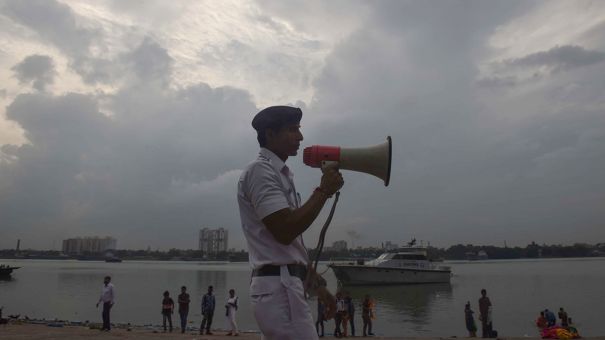 <div class="paragraphs"><p> A river traffic police personnel makes an announcement as part of precautionary measures against Cyclone Asani, on the banks of Ganga river, in Kolkata, Tuesday, 10 May.</p></div>