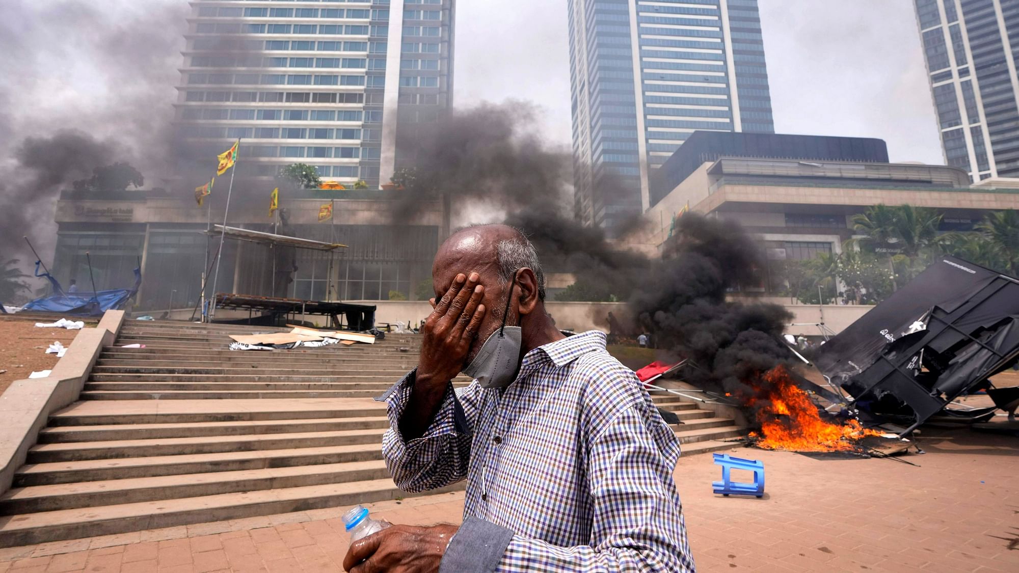 <div class="paragraphs"><p>A Sri Lankan man reacts to tear gas as he walks past the vandalised site of anti-government protests outside President Gotabaya Rajapaksa's office in Colombo on 9 May. </p></div>