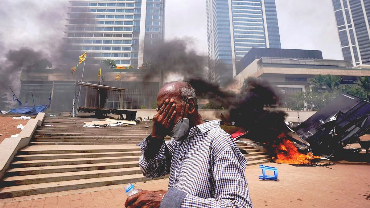 <div class="paragraphs"><p>A Sri Lankan man reacts to tear gas as he walks past the vandalised site of anti-government protests outside President Gotabaya Rajapaksa's office in Colombo on 9 May. </p></div>