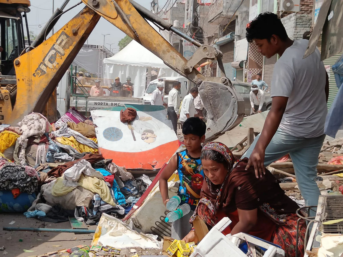 <div class="paragraphs"><p>A vendor rummages in the debris to find unharmed goods as demolition of structures continues in the background in Jahangirpuri, New Delhi, on Wednesday, 20 April.</p></div>