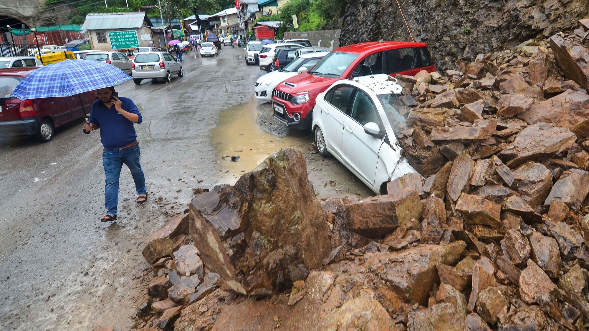<div class="paragraphs"><p>Shimla: A man walks past vehicles buried under debris after a landslide due to heavy rainfall in Shimla, Wednesday, 6 July.</p></div>