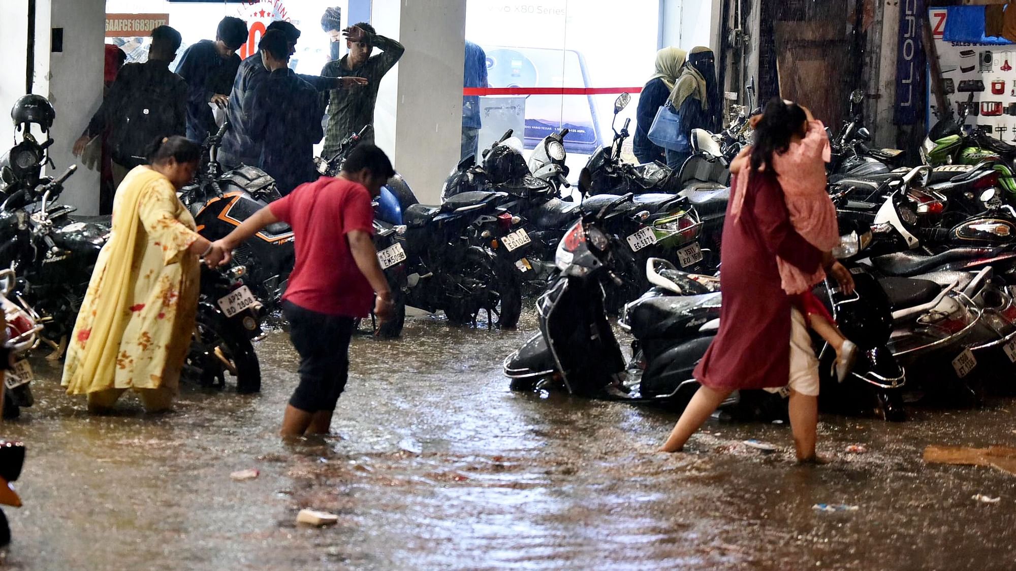 <div class="paragraphs"><p>Commuters wade through a waterlogged street following rain in Hyderabad.</p></div>