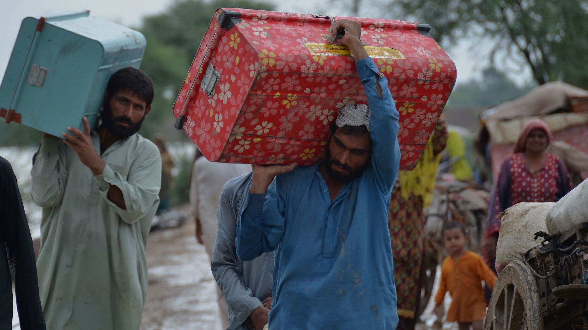 <div class="paragraphs"><p>Displaced people carry belongings after they salvaged usable items from their flood-hit home as they wade through a flooded area in Jaffarabad, a district of Pakistans southwestern Baluchistan province, Thursday, Aug. 25, 2022.</p></div>
