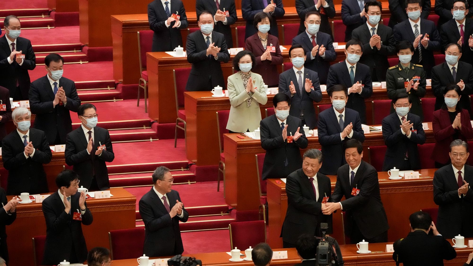 <div class="paragraphs"><p>Chinese President Xi Jinping is congratulated by Li Zhanshu as other delegates applaud after he is unanimously elected as President during a session of Chinas National People's Congress (NPC) at the Great Hall of the People in Beijing, on Friday, 10 March.</p></div>
