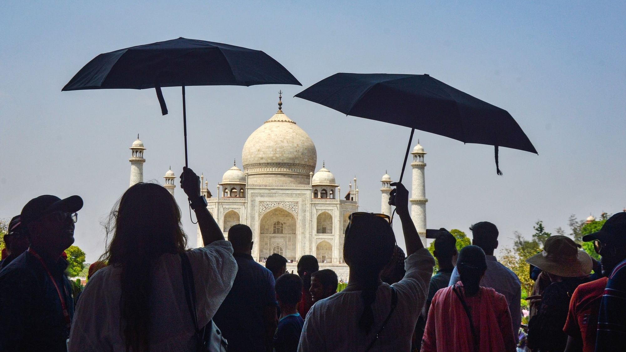 <div class="paragraphs"><p>Agra: Tourists use umbrellas to shield themselves from the hot summer sun during their visit to the Taj Mahal, in Agra on Monday, 17 April.</p></div>