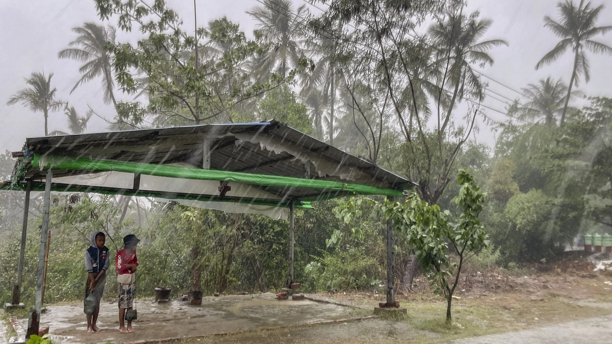 <div class="paragraphs"><p>Two children stand under a roadside shelter to protect themselves from rain before Cyclone Mocha hits in Sittwe, Rakhine State, on Sunday, 14 May.</p></div>