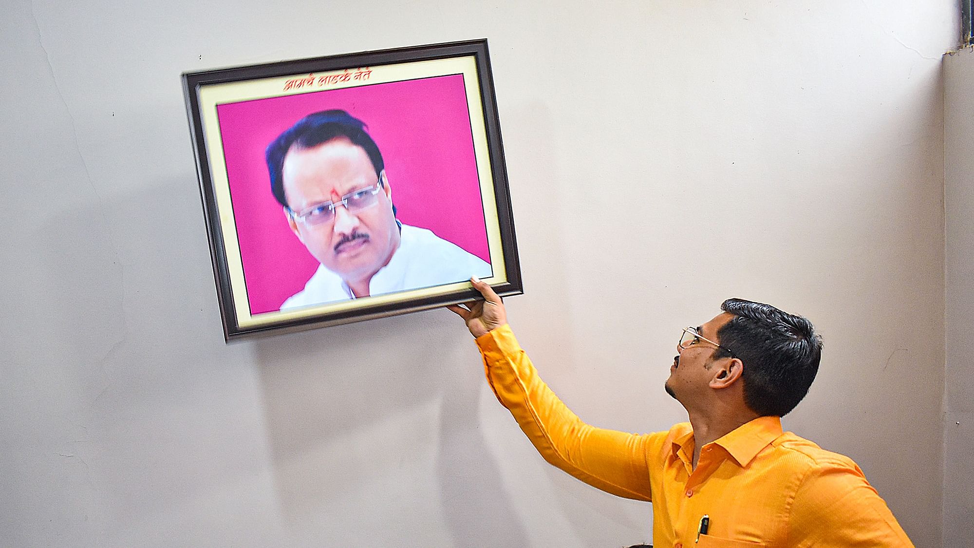 <div class="paragraphs"><p> Nationalist Congress Party (NCP) workers remove a photo of Maharashtra Deputy Chief Minister Ajit Pawar from the party office as part of a protest, in Solapur, Monday, July 3, 2023.</p></div>