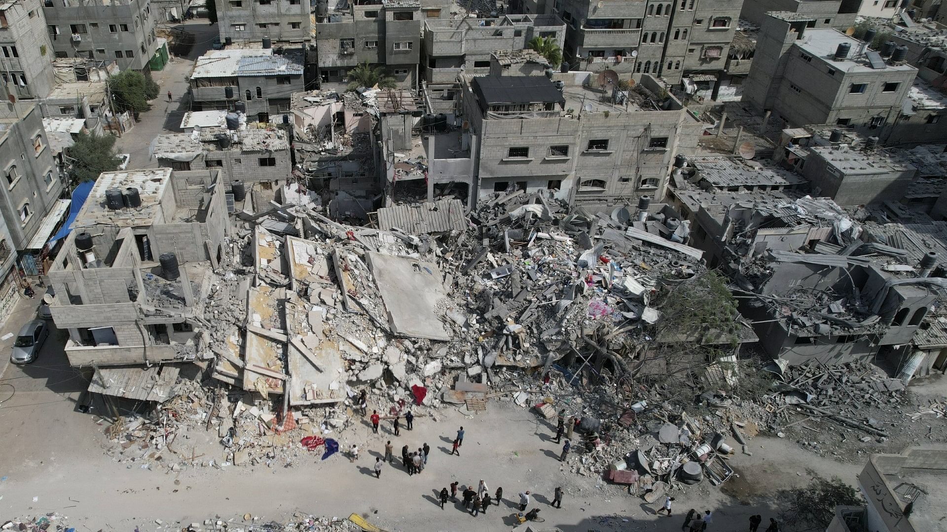 <div class="paragraphs"><p>Palestinians stand by the building destroyed in an Israeli airstrike in Nuseirat camp in the central Gaza Strip.&nbsp;</p></div>