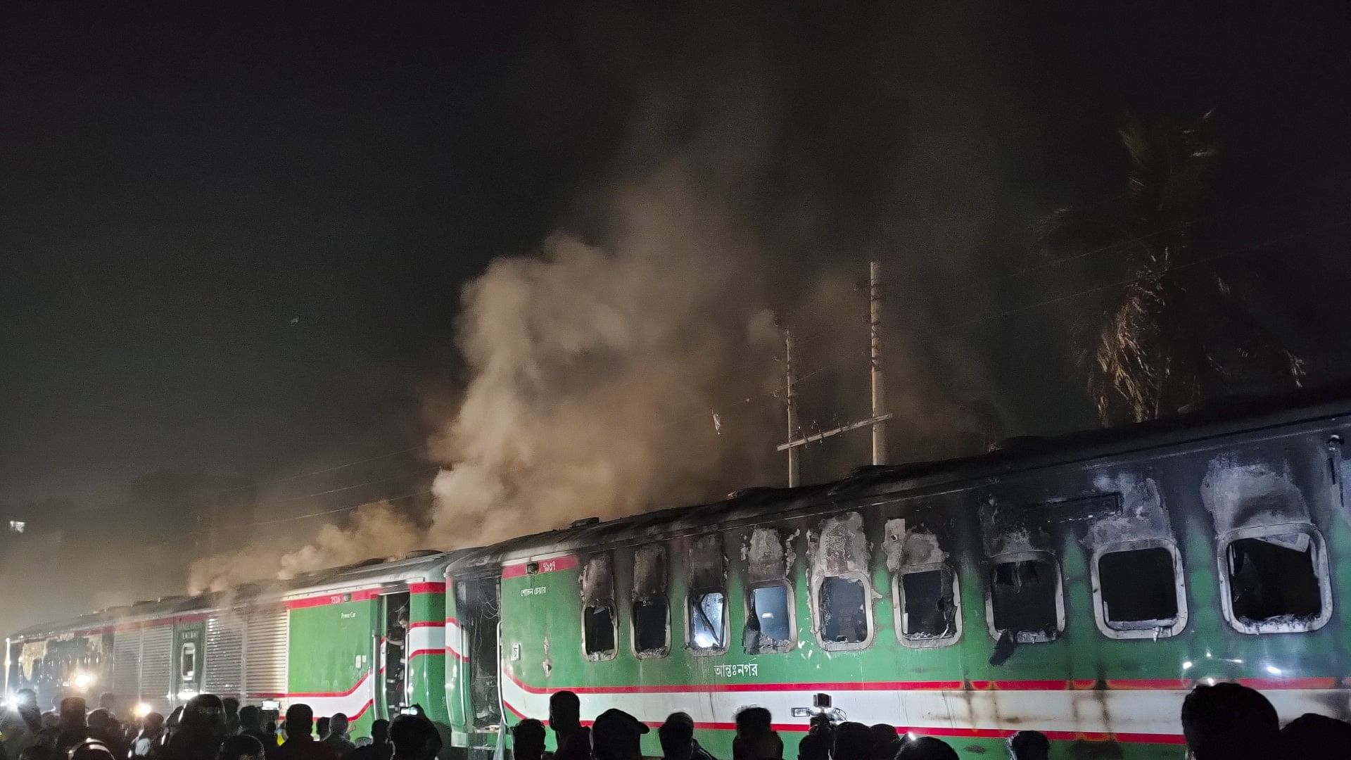 <div class="paragraphs"><p>People stand near a burning passenger train at Gopibagh in Dhaka, Bangladesh on Friday, 5 January 2024. </p></div>