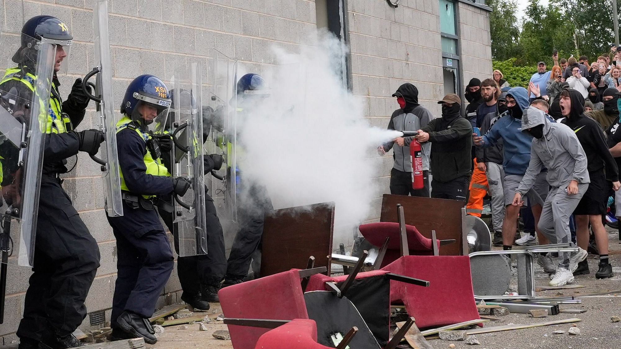 <div class="paragraphs"><p>A protester uses a fire extinguisher on police officers as trouble flares during an anti-immigration protest outside the Holiday Inn Express in Rotherham, England on Sunday, 4 August.&nbsp;</p></div>