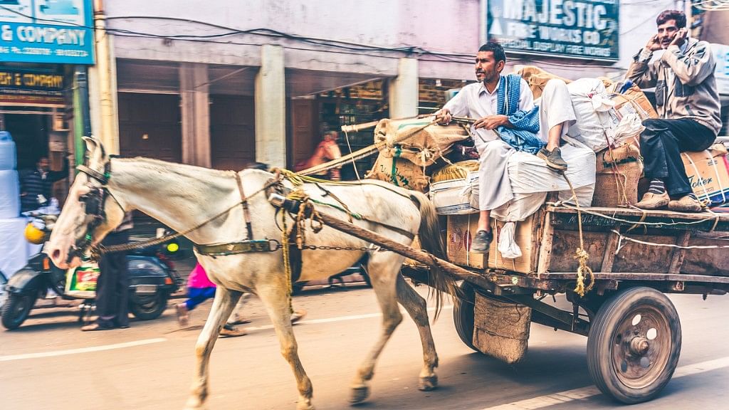 Working horse drawn cart loaded with sacks, bags and boxes ridding in a street of Old Delhi.