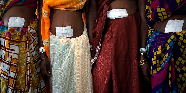 Women, who underwent sterilisation surgery at a government mass sterilisation camp, pose for pictures inside a hospital at Bilaspur district in Chhattisgarh on November 14, 2014.