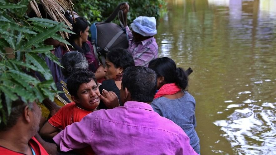 A boy cries as he sits in a boat after being rescued by volunteers in Kerala.&nbsp;