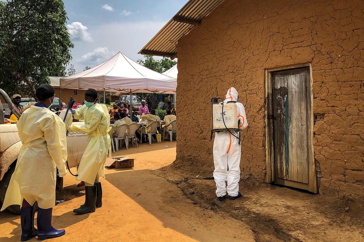 A worker from the World Health Organization (WHO) decontaminates the doorway of a house.