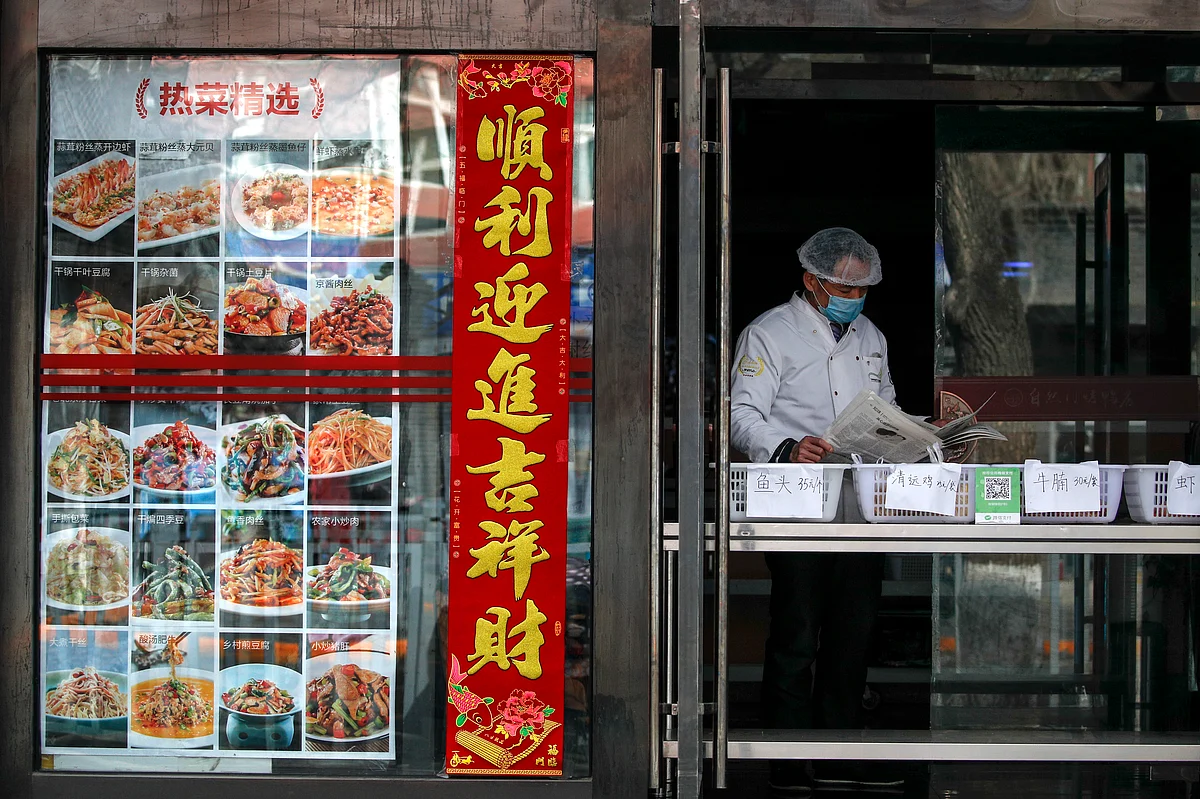 An employee wearing protective gear reads a newspaper at a restaurant only offering take-out orders following the coronavirus outbreak in Beijing, Sunday, March 1, 2020.