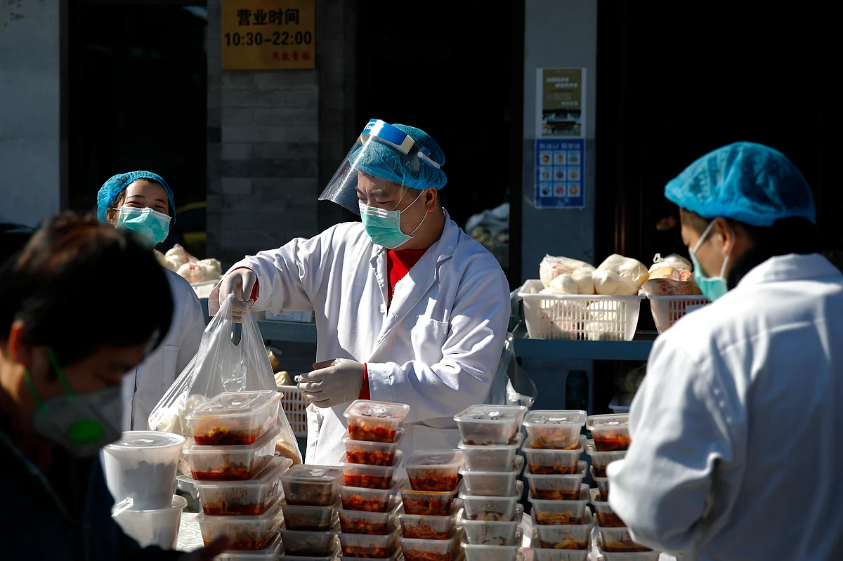 Workers wearing protective face masks pack food orders for customers outside a restaurant only offering take-out business to prevent people gathering following the coronavirus outbreak in Beijing, Sunday, March 1, 2020.