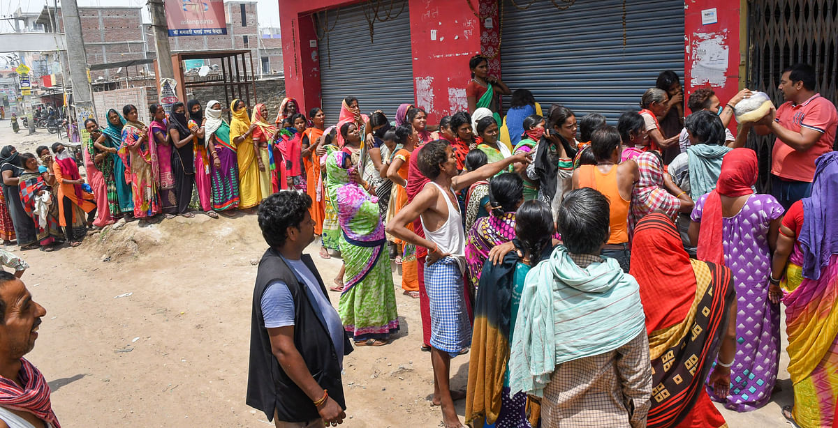 People stand in queues ignoring social distancing to collect essential food items by volunteers during the nationwide lockdown to curb the spread of coronavirus, in Patna on Saturday, 18 April.